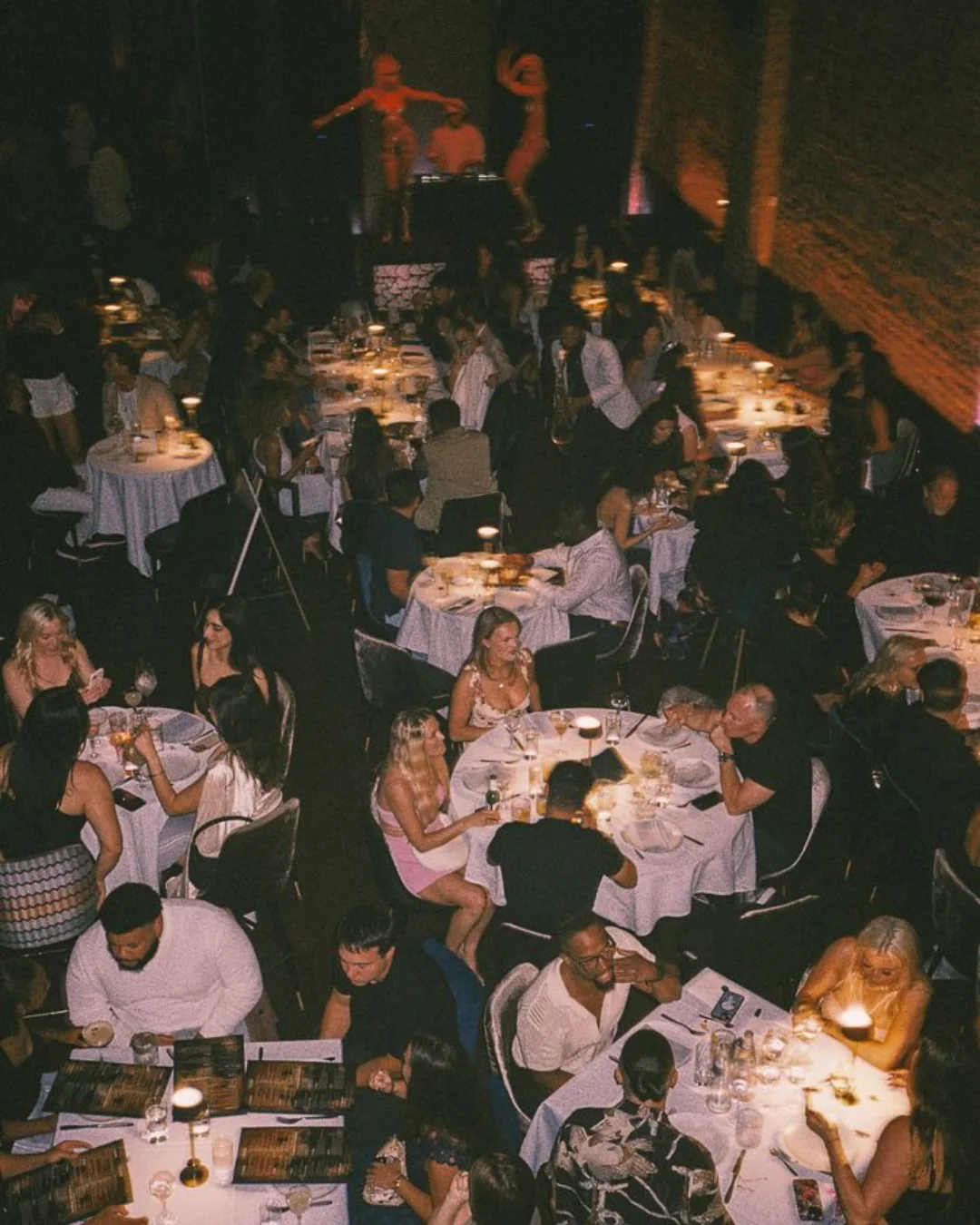 Guests dining together as a performer moves between the tables
