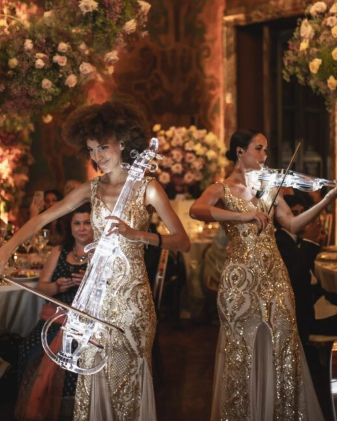 Violinists performing among flowers at a dinner venue
