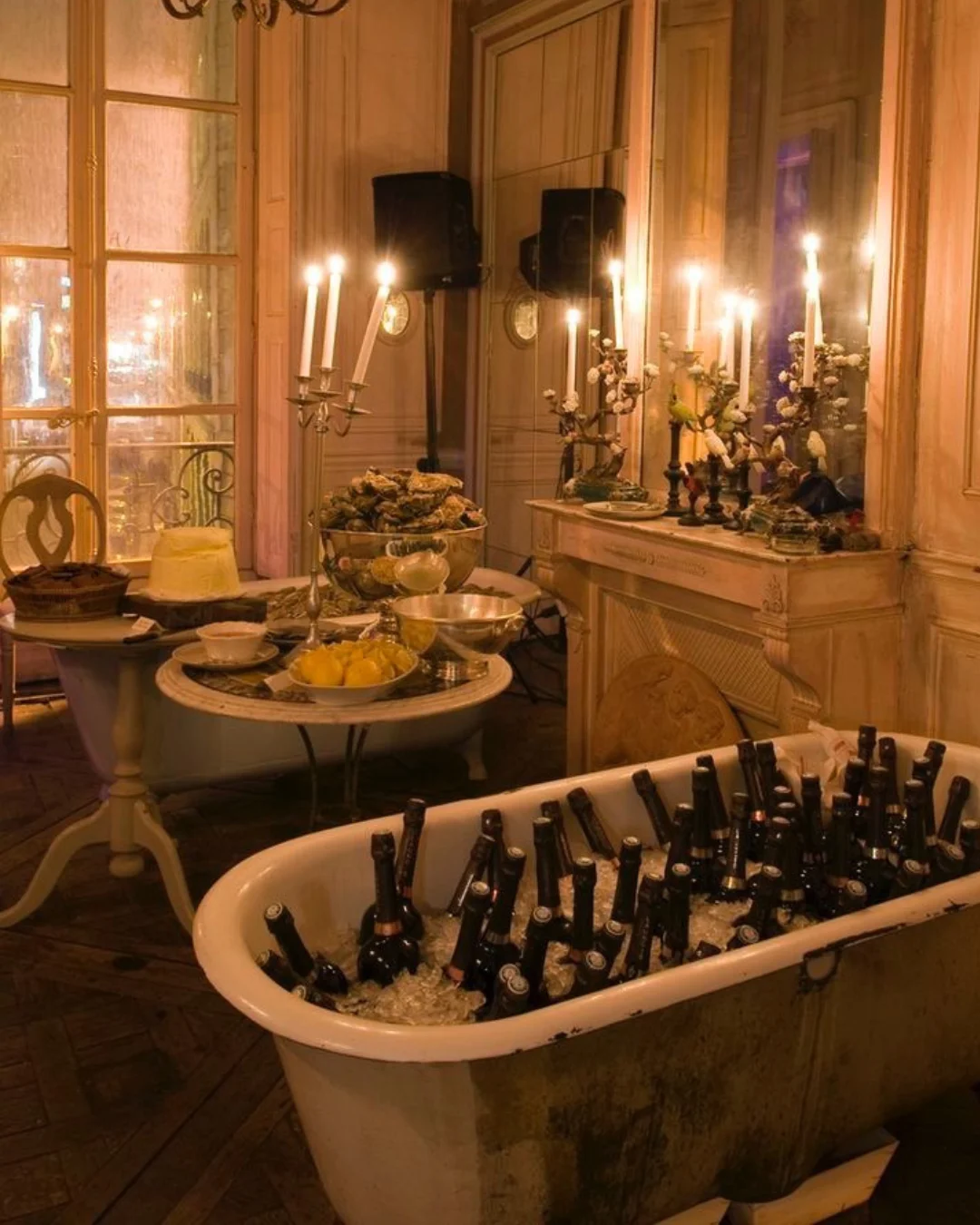 A candlelit room with dining tables and bottles chilled in a bathtub