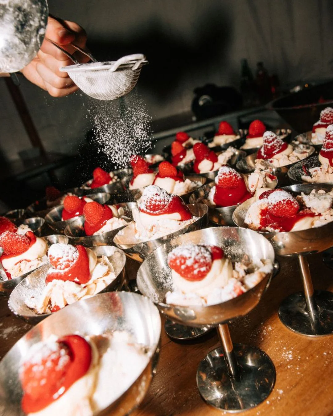 Berry desserts being finished with a dusting of icing sugar